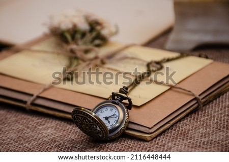 Photo in retro style. Craft envelopes and old letters tied with jute thread and decorated with dried flowers, an old clock lies nearby