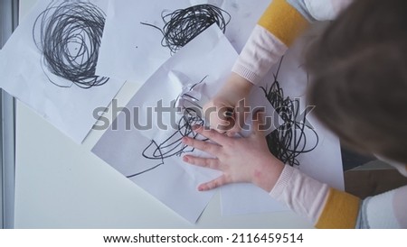 Young Troubled Caucasian Kid Child Girl Drawing Disturbing Chaotic Black Shapes and Circles on Piece of Paper
