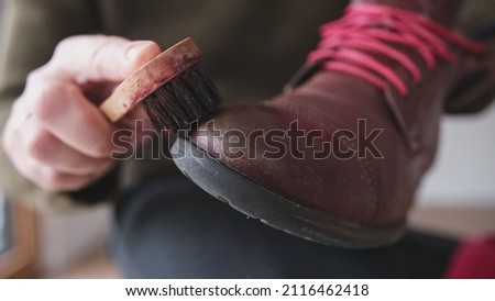 Caucasian Male Using Soft Horsehair Brush to Apply Brown Shoe Shine Wax to Protect and Impregnate Leather Boots Shoes Wide Royalty-Free Stock Photo #2116462418