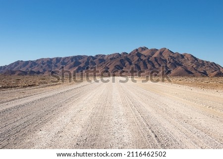 close up of a washboard gravel road in Namibia. Naukluft mountain range in the background. Bright blue sky