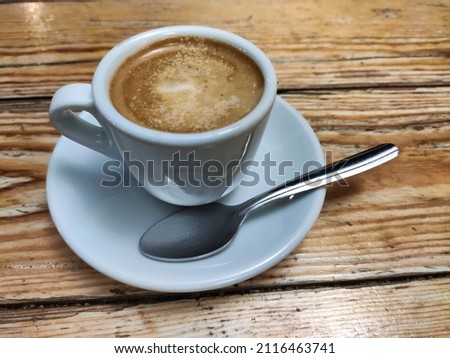 A cup of coffee with a teaspoon on a wooden table. Asturias, Spain