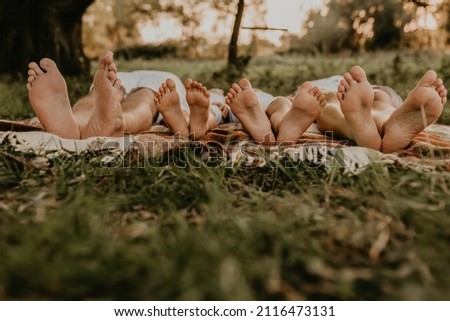 close-up bare feet of whole family resting. cheerful happy family dad mom daughters lay laying on grass picnic plaid have fun at summer outdoors together. father mother sisters parents barefoot people Royalty-Free Stock Photo #2116473131