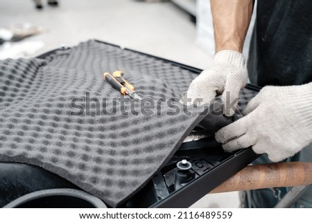 Auto service worker installing soundproofing foam material on car door trim from inside, tuning car sound or installing noise insulation Royalty-Free Stock Photo #2116489559