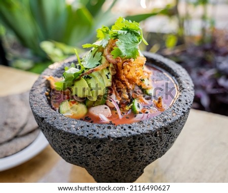 delicious mexican agua chile rojo with shrimp, squid, octopus and clam prepared with red chiles and avocado on top placed over molcajete. Royalty-Free Stock Photo #2116490627
