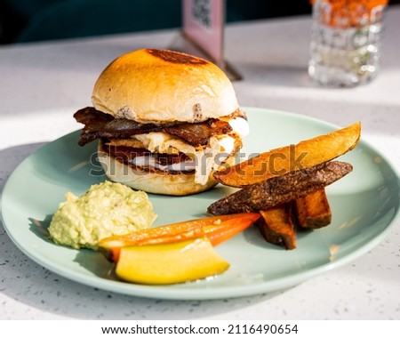 Delicious slider with egg and bacon served with french fries and a portion of guacamole.