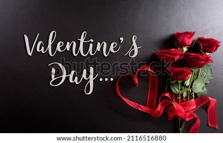 Love and Valentine's day concept made from red rose  and heart ribbonwith the text on black wooden background.