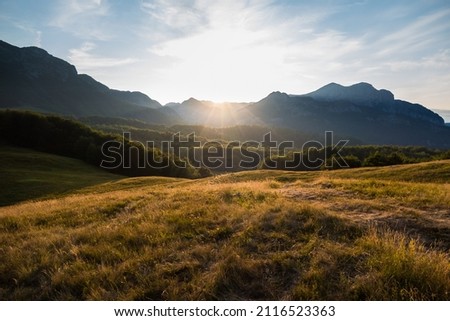 Wonderful autumn landscape in mountains. Grassy field and rolling hills. Sunset. Royalty-Free Stock Photo #2116523363