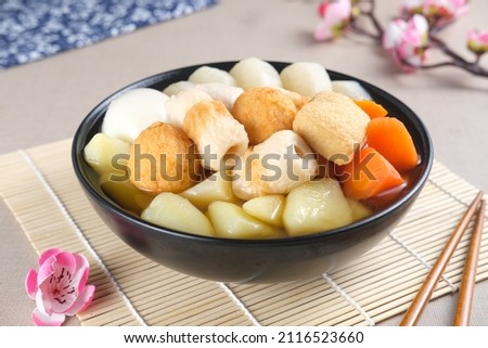 Traditional Japanese Oden with radishes, carrots, potatoes, chikuwa, meatball, fish cakes and boiled egg of food stewed in a black bowl. Selective focus.