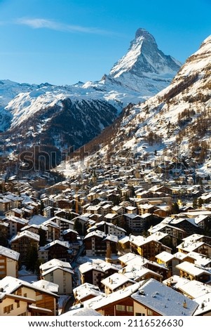 Picturesque winter view of alpine township of Zermatt surrounded by snow-capped Alps on background of sharp peak of Matterhorn, canton of Valais, Switzerland