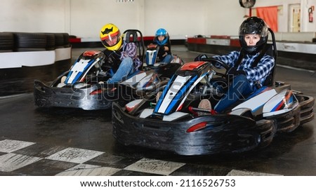 Jolly adult female go-cart racer crossing finish line Royalty-Free Stock Photo #2116526753