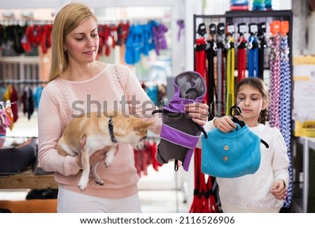 Cheerful positive woman with dog in pet store during shopping with daughter