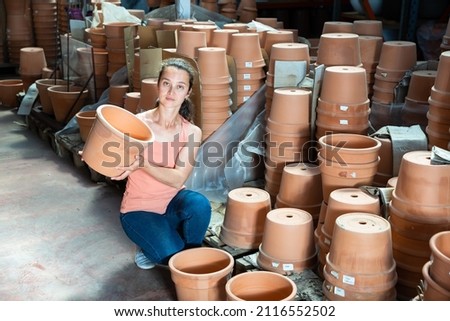 Woman chooses pots clay pots in store warehouse. High quality photo