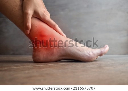 Inflammation of Asian young man’s ankle joint and foot. Concept of joint pain, osteoarthritis or gout. Royalty-Free Stock Photo #2116575707