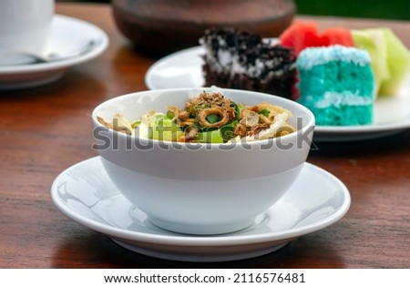 Close up of Bubur Ayam, chicken porridge, on wooden table Royalty-Free Stock Photo #2116576481