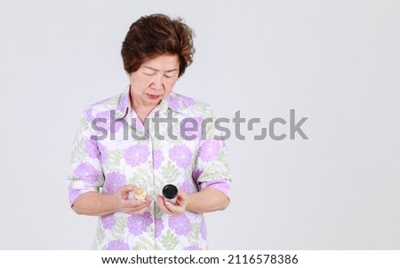 Elderly aunt, Senior Asian woman holding pills provided from hospital practitioner as antibiotic medicine for virus treatment on white background concept