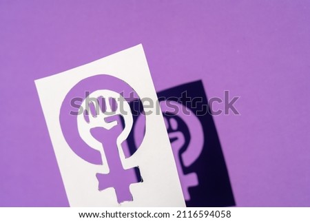 Symbol of the struggle of feminism on a purple background, clenched fist of a woman in the march protests for women's rights
