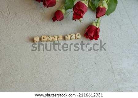 the words I love you from letters on a blurred concrete background with roses out of focus, the concept of Valentine's Day and March 8