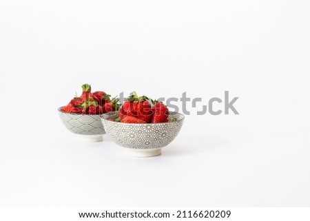 Strawberries in round plates, arranged on a white background.