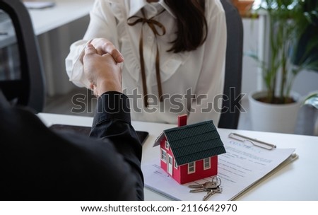 Estate agent and customer shaking hands after fafter signing contract about home insurance and investment loan.