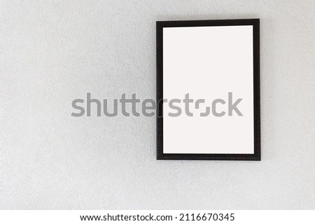 an empty picture with a wooden frame hangs on a light wall in the room