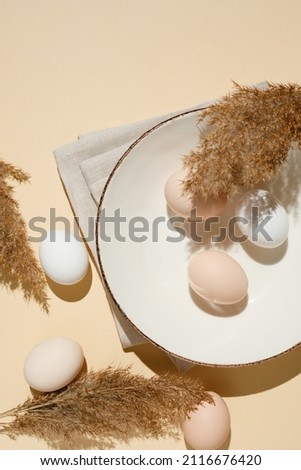 fresh eco-friendly farm chicken eggs in a plate on a beige background. Minimalistic style. Easter. Top view. Copy space