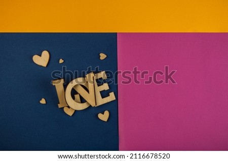Love word, small hearts on colorful paper background. Top view of Valentine's Day. Copyspace.