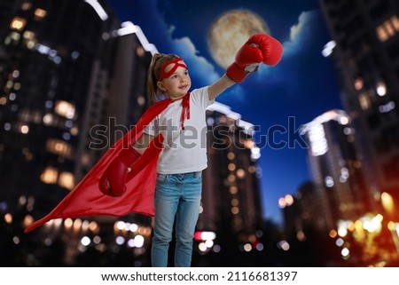 Little girl wearing superhero costume and beautiful cityscape in night on background