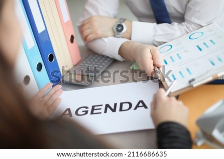Man and woman sitting at table with documents with agenda closeup