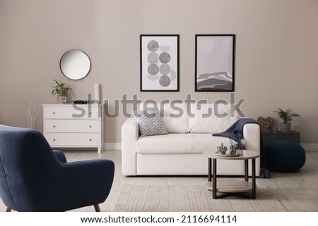 Stylish living room interior with white sofa, armchair and small coffee table