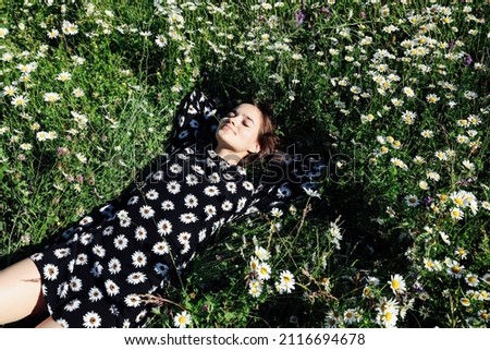 woman lies in the grass with chamomile flowers