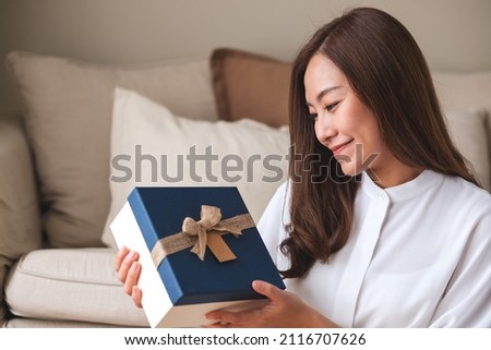Portrait image of a young woman holding and looking at a present box