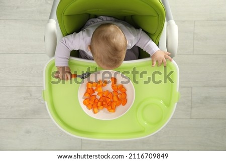 Cute little baby eating carrot, top view