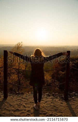 Young woman in her thirties standing with open arms in the hill  Royalty-Free Stock Photo #2116715870