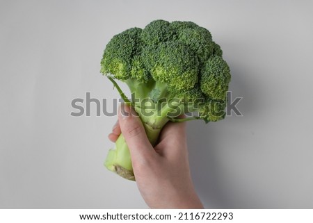 Woman's hand holding green bunch of broccoli isolated on white background. Raw food diet and vegetarian concept.Close up