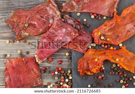 Jerky with spices on a wooden table. Beer snack. Detail for design. Design elements. Macro. Full focus. Background for business cards, postcards and posters. Food object design. 