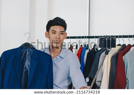 Young Asian man blogger is broadcasting a video for selling clothes online.
