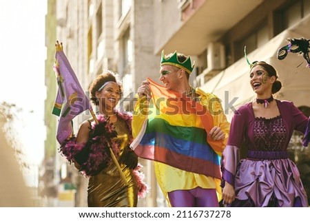 Group of cheerful friends celebrating Mardi Gras and having fun on street parade during the festival.