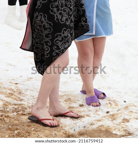Two white women legs in towels are standing in the snow. Winter sports outdoor.