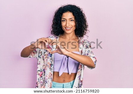 Young latin girl wearing casual clothes smiling in love showing heart symbol and shape with hands. romantic concept. 