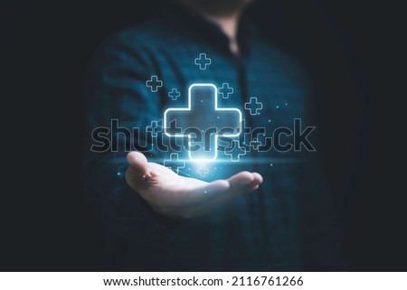 Businessman holding virtual blue plus sign for positive thinking mindset or healthcare insurance symbol concept. Royalty-Free Stock Photo #2116761266