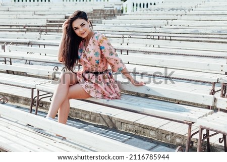 beautiful brunette woman in a dress with flowers walks in the park