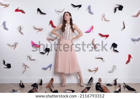 Fashionable young woman surrounded by many different high heel shoes indoors Royalty-Free Stock Photo #2116793312