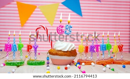 A sixty-five year old happy birthday card on a pink background, with a number in a cupcake. Beautiful happy birthday background with number 65 with burning candle. Festive background with colorful