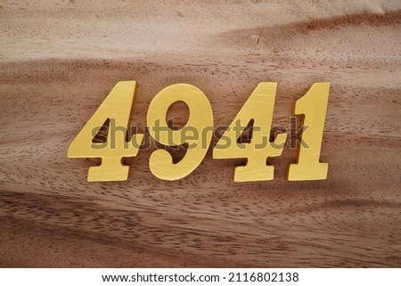 Wooden Arabic numerals 4941 painted in gold on a dark brown and white patterned plank background.