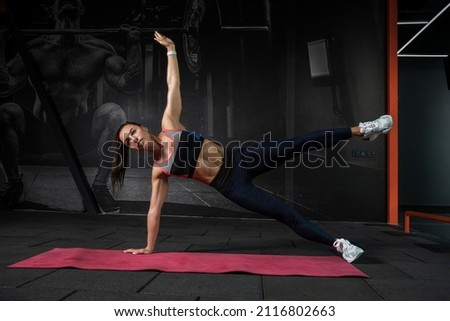 Young woman performing side plank hip abduction at gym Royalty-Free Stock Photo #2116802663