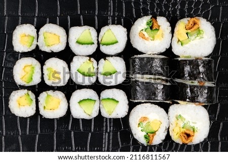 A top view of sushi nigiri, maki, sashimi rolls on a black plate