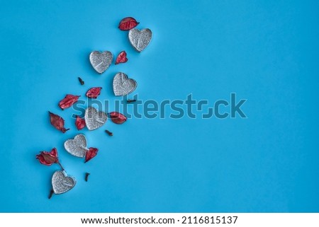 Heart shaped candles, rose petals on a blue background. View from above. Place for text