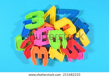 Heap of plastic colored numbers on a blue background close up