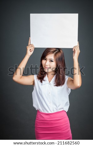 Asian girl hold blank sign over her head on gray background