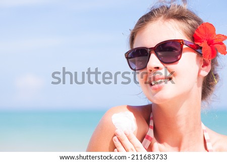 Young woman in sunglasses putting sun cream on shoulder